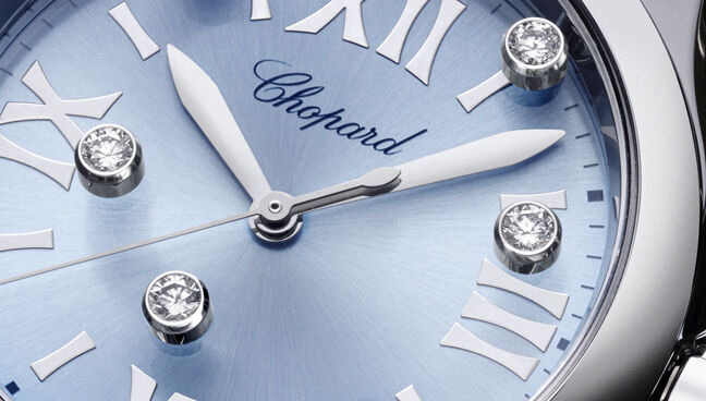 Detail shot of Chopard Happy Sport watch dial with floating diamonds and Roman numerals on a sunburst blue background